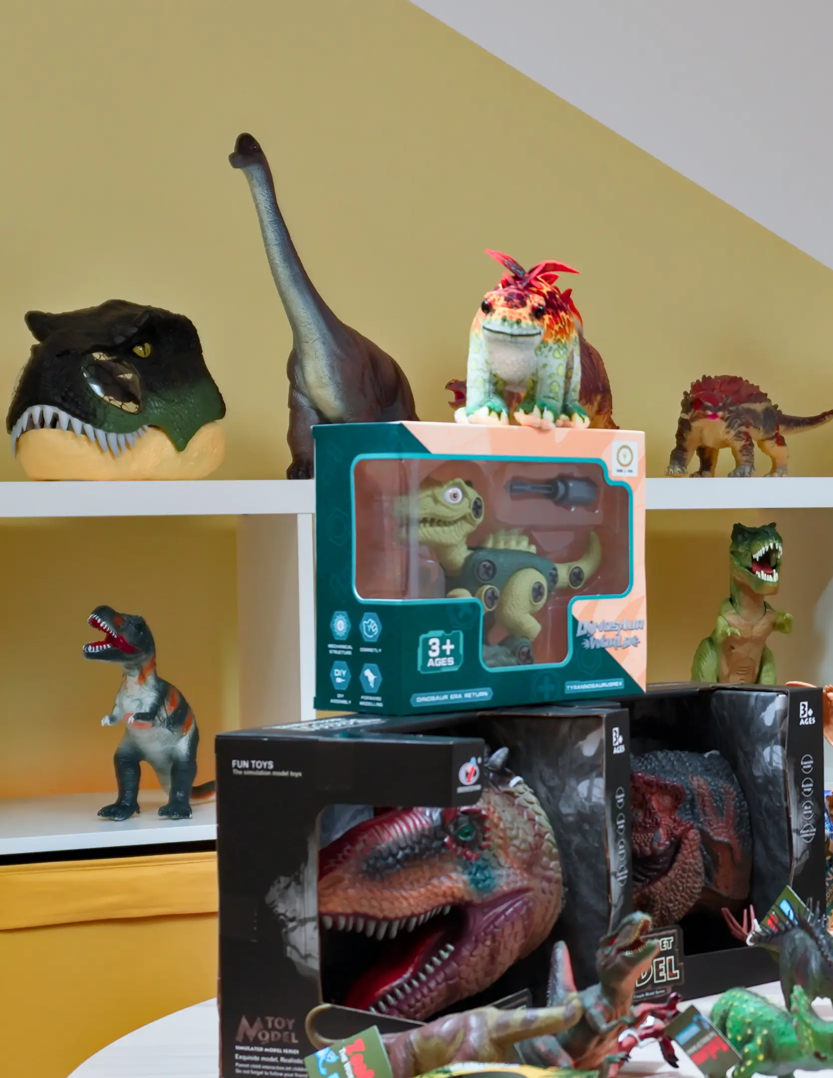 Pestré dinosauří hračky a masky vystavené na polici